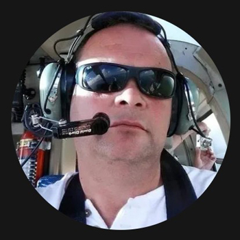 man wearing sunglasses and headphones in a helicopter cockpit showcasing a professional pilot looking confident and focused with seven aviation tools in view