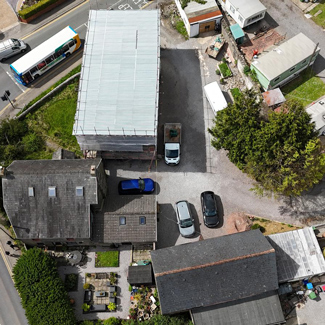 aerial view of a residential area featuring multiple buildings and parked cars including a blue vehicle several plants and a bus nearby showcasing twelve parking spots available