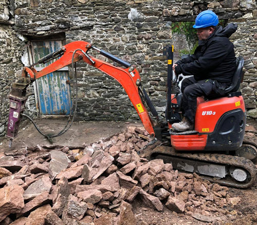 excavator operator breaking rocks near a stone wall 4 construction site tools