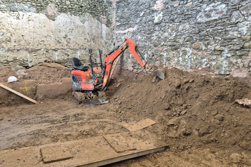 excavator digging soil in construction site with stone walls and wooden planks showing eight construction techniques