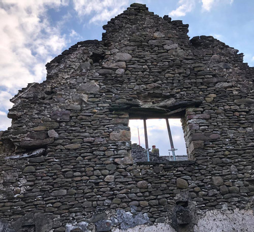 ruined stone wall with an arched window under a cloudy sky showcasing the remains of a historic structure reflecting the passage of time and nature's impact on two centuries of architecture