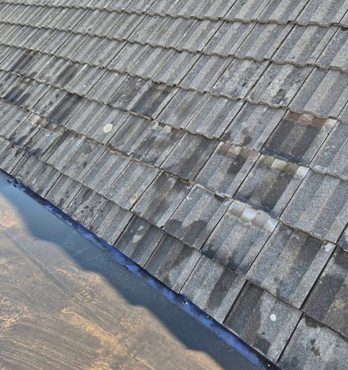 aerial view of a weathered roof with unevenly arranged tiles showing signs of wear and moisture in a flat roofing area ideal for roof inspection maintenance and repair