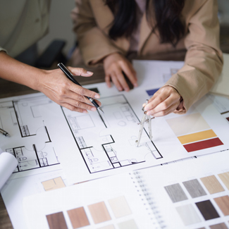 two hands working on architectural plans with color swatches and design choices discussing layout options and nine possible design themes