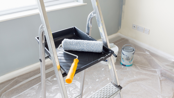 ladder with paint tray and roller in a room under renovation featuring paint cans and protective covering to simplify three painting tasks