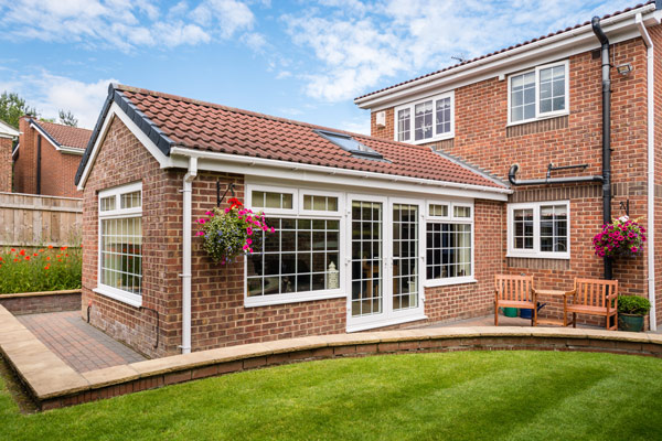 a beautiful brick house extension with large windows surrounded by a well-maintained garden showcasing vibrant flowers and inviting seating perfect for family gatherings and outdoor enjoyment