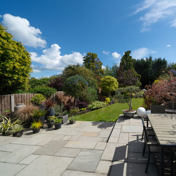 a beautiful garden view with vibrant plants flowers and blue sky featuring patio stones and outdoor seating perfect for relaxation and outdoor activities gardening design