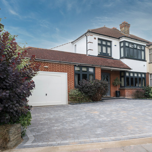 modern house with driveway and garden featuring three windows and green plants